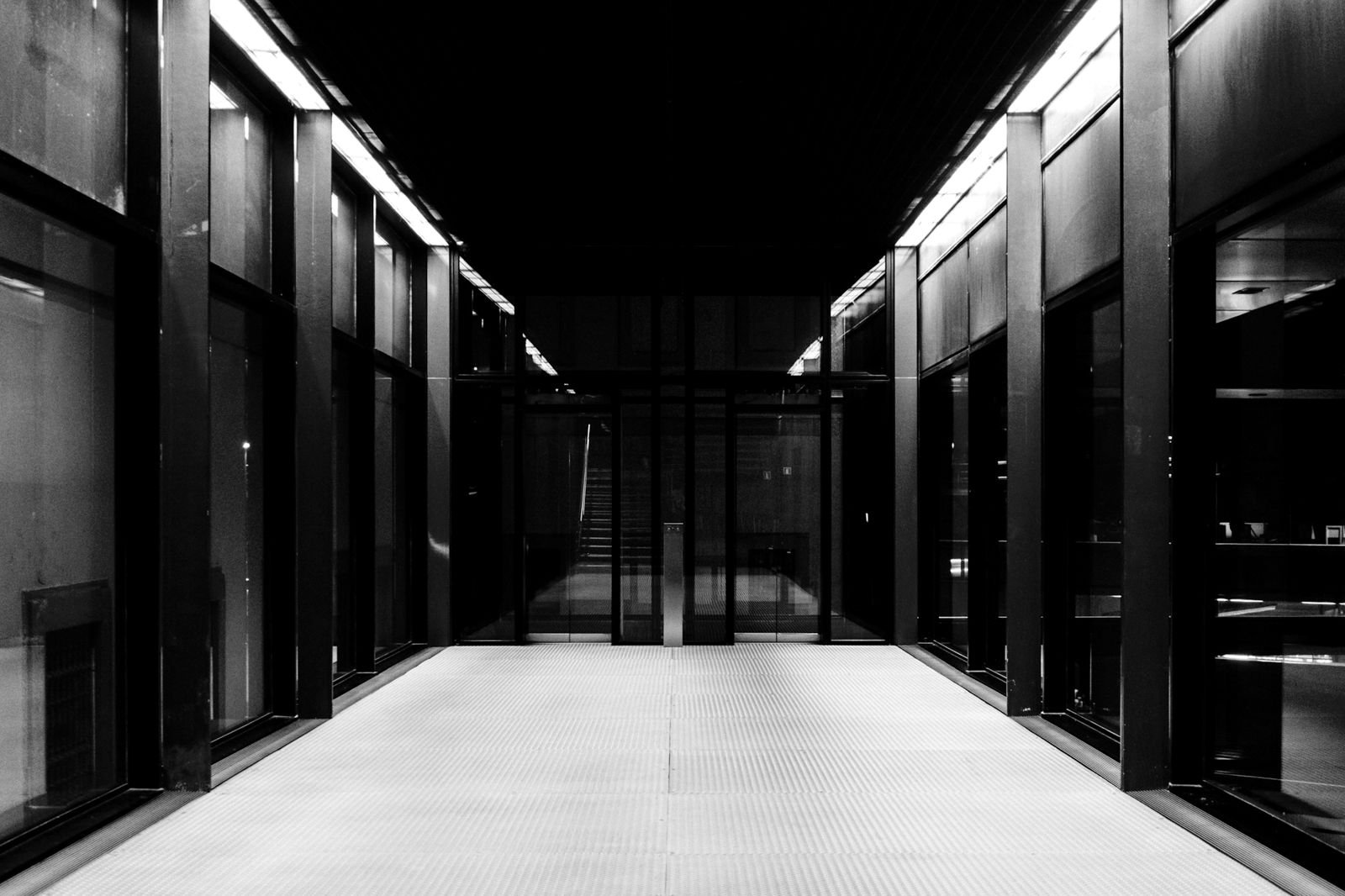 A long data center corridor between glass-walled server rooms