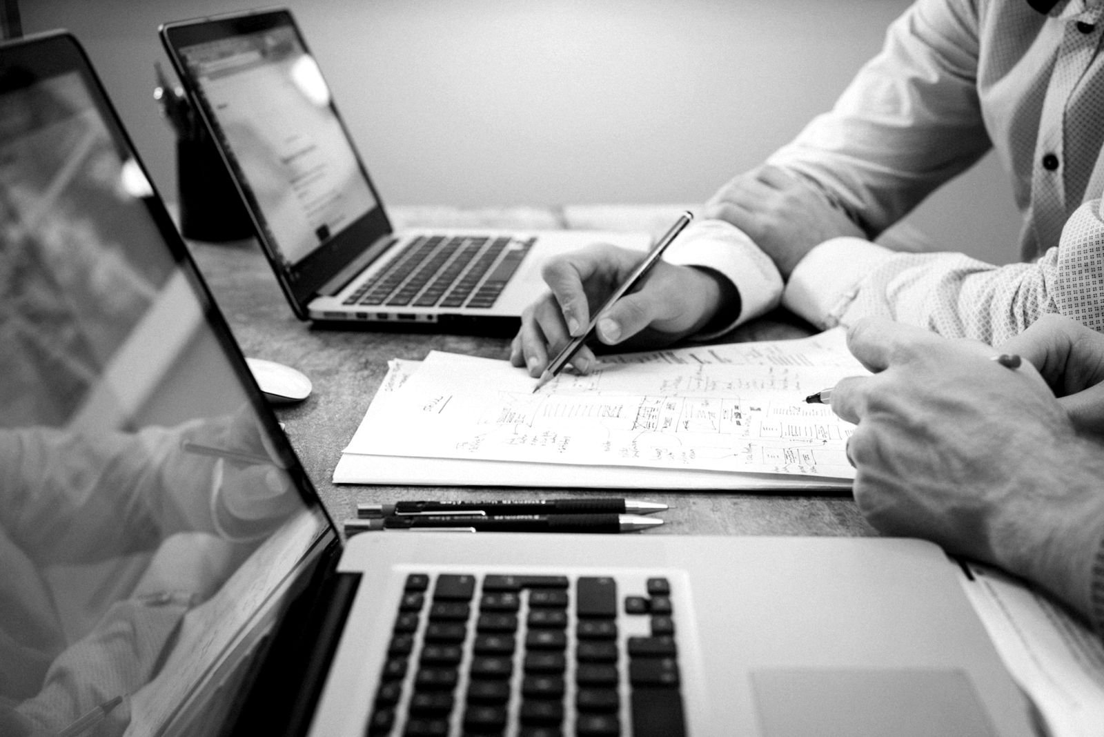 Two people reviewing printed figures next to laptops